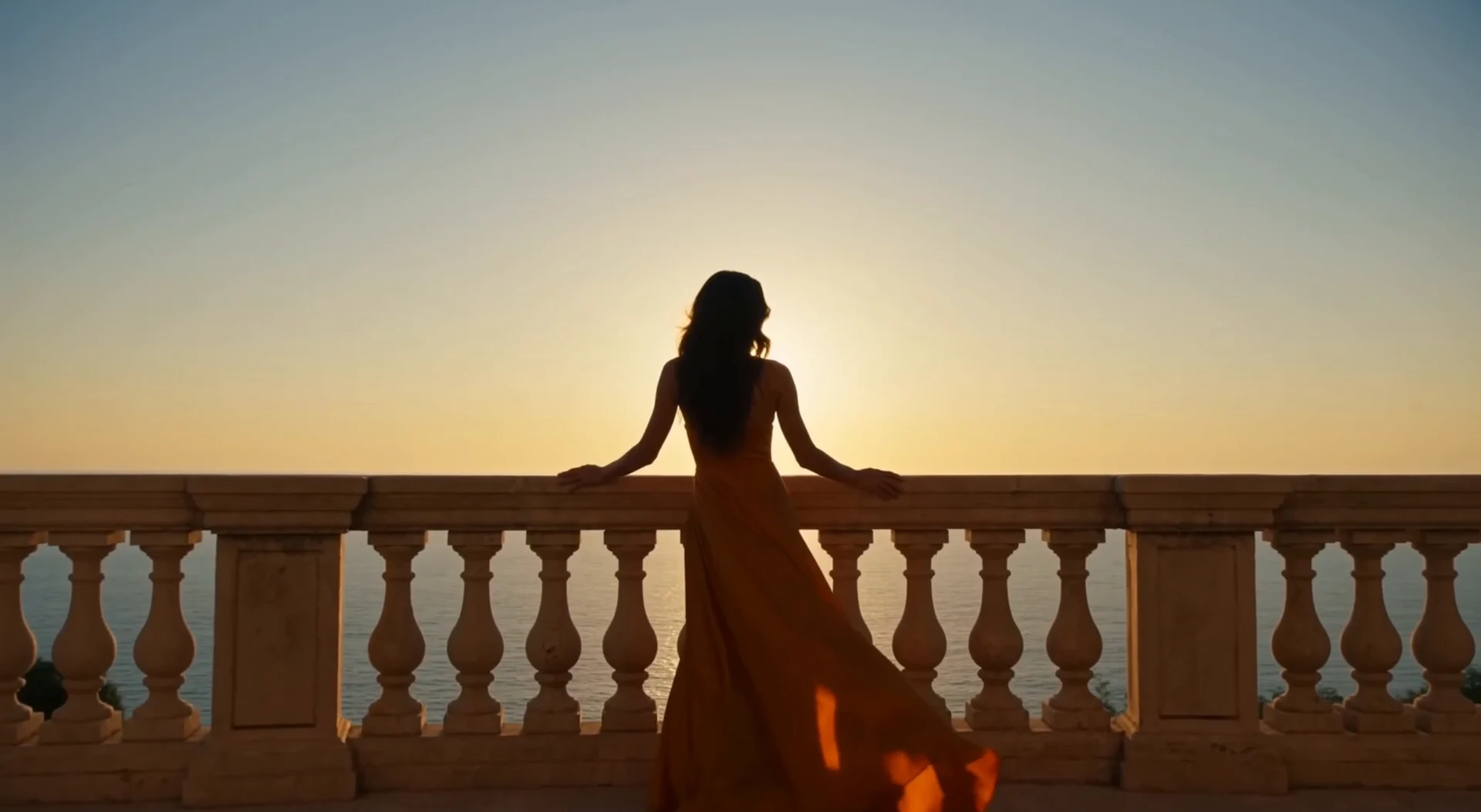 Woman in a flowing amber dress overlooking the Mediterranean at sunset